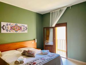 um quarto com paredes verdes e uma cama com toalhas em Angelo Apartments & Rooms em Trapani