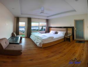 a bedroom with a bed and a couch and wooden floors at Eat and Read Hotel in Skardu