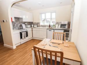 uma cozinha com uma mesa de madeira com 2 cadeiras e uma sala de jantar em 3 Rothbury Place em Lytham St Annes