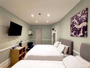 um quarto de hotel com duas camas e uma televisão em The Swan Hotel em Hythe