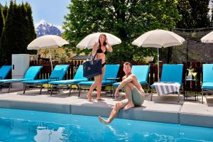 Eine Frau steht neben einem Mann, der in einem Schwimmbecken sitzt. in der Unterkunft HOTEL SONNBLICK Kaprun, Salzburg - including Summer Card in Kaprun