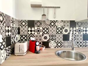 a kitchen with black and white tiled walls and a sink at Bleu Soleil Rochefort 3 étoiles in Rochefort