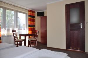 ブコビナ・タトシャンスカにあるGościniec u Groszkaのテーブルと椅子、窓が備わるホテルルームです。