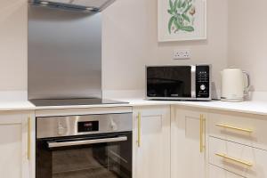 a kitchen with white cabinets and a microwave and a stove at Monmouth Street Bath in Bath