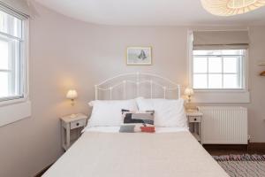 a bedroom with a white bed with two windows at Monmouth Street Bath in Bath