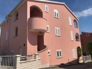 un grand bâtiment rose avec une grande fenêtre dans l'établissement Apartments IRENA, à Vodice