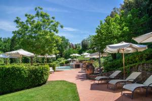 a patio with chairs and umbrellas and a pool at Il Torrino Country Resort in Montaione