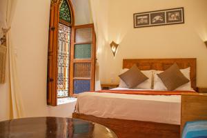 una camera da letto con un letto, un tavolo e una finestra di Riad Dar Tamlil a Marrakech