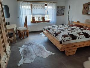 Ferienwohnungen Eisler في آبنسبرغ: غرفة نوم مع سرير مع بطانية بقر على الأرض