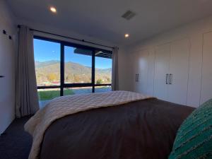 a bedroom with a bed and a large window at Altura Apartment Bright in Bright