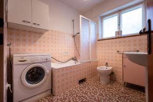 ein Badezimmer mit Waschmaschine und Toilette in der Unterkunft La Marmote Albergo Diffuso di Paluzza Naunina in Paluzza