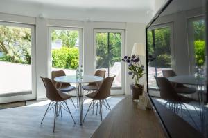 a dining room with two tables and chairs and windows at Muschel 2 in Ahrenshoop