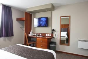 a hotel room with a bed and a television at The Oakwood Hotel by Roomsbooked in Gloucester