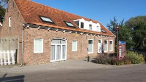 un edificio de ladrillo con puertas blancas y techo rojo en Studio@Domburg, en Domburg