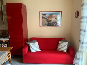 eine rote Couch in einem Wohnzimmer mit Bild in der Unterkunft Holiday House Boschette in San Felice del Benaco