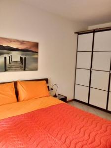 ein Schlafzimmer mit einem orangenen Bett und einem Gemälde an der Wand in der Unterkunft Holiday House Boschette in San Felice del Benaco