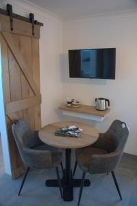 Habitación con mesa, 2 sillas y TV. en Auberge la Hutte Lurette, en Paliseul
