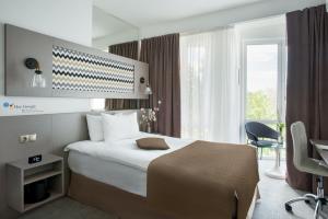 una camera d'albergo con letto, scrivania e finestra di Thomas Albert a Chişinău
