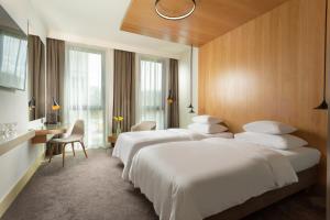 Habitación de hotel con 3 camas y escritorio. en Hotel Golf Prague en Praga