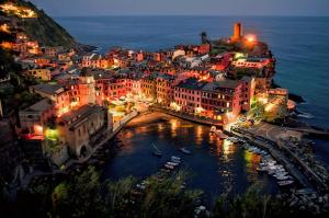 a city lit up at night with boats in the water at Santa Marta Rooms in Vernazza