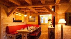 a dining room with a long table and red chairs at Madame Vacances Chalet Marmotte in LʼHuez