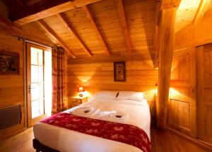 a bedroom with a bed in a wooden room at Madame Vacances Chalet Marmotte in LʼHuez