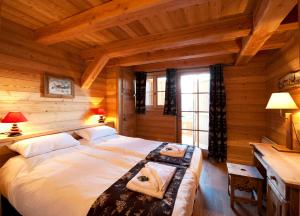 a bedroom with a large bed in a log cabin at Madame Vacances Chalet Marmotte in LʼHuez