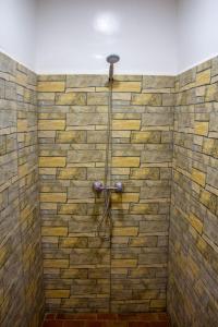 a bathroom with a shower with a stone wall at Auberge oued dades in Boumalne