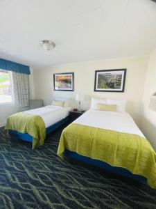 a hotel room with two beds and two windows at Bar Harbor Villager Motel - Downtown in Bar Harbor