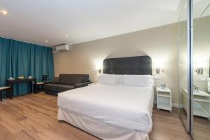 a bedroom with a large white bed and a couch at Senator Barcelona Apartments in Barcelona
