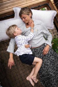 a woman holding a young boy on a bed at Bain de forêt - Lodges Cosy & Spa in Neufchâtel-Hardelot
