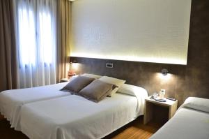 a bedroom with a large white bed and a window at Hotel Oriente in Teruel