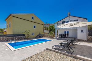 a house with a swimming pool and an umbrella at Holiday house San Michele in Krk