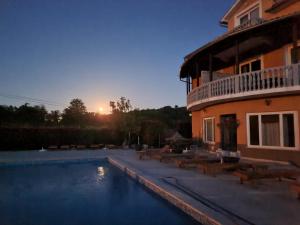 a swimming pool in front of a house with the sunset at Apartments Šeherzada in Pula