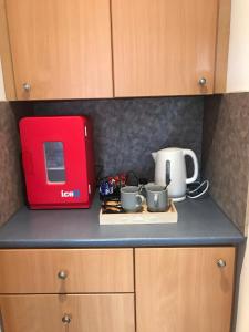 a kitchen counter with a red toaster and some cups at Exclusive Private double room, en-suite wet room Private entrance in Forres