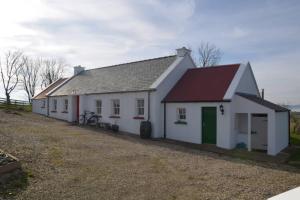 een wit huis met een rood dak en een fiets geparkeerd buiten bij Cecil's Cottage, Ballynary, Buncrana by Wild Atlantic Wanderer in Buncrana
