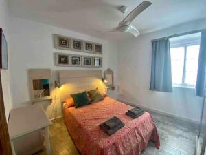 Un dormitorio con una cama y un ventilador de techo. en Anticuario en el Teatro Falla, en Cádiz