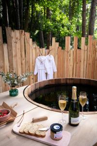 a table with two glasses of wine and a bottle of champagne at Bain de forêt - Lodges Cosy & Spa in Neufchâtel-Hardelot