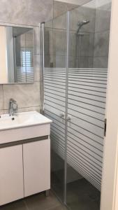 a bathroom with a glass shower and a sink at Isramax low-cost apartment near the sea. in Bat Yam