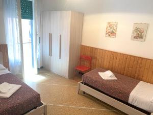 1 dormitorio con 2 camas y silla roja en Marie Claire, en Levanto