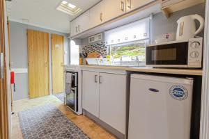 a kitchen with white cabinets and a microwave at Skye Holiday Chalets C1 in Uig