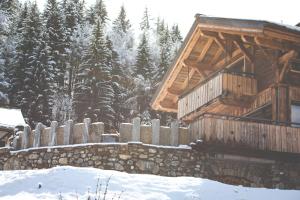 una cabaña de madera en la nieve con una valla en Les Mazots des Fées, en Morzine
