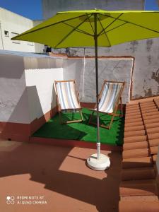 Mexilhoeira Grande的住宿－Casa da Vila，天井上绿伞下的两把椅子