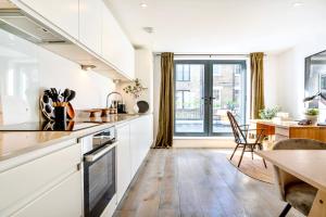 una cucina con armadi bianchi e una sala da pranzo con tavolo di Be London - The Bloomsbury Residences a Londra