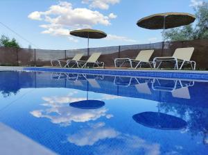 a group of chairs and umbrellas next to a swimming pool at Los Laureles Casa Rural in Urda