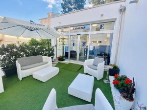 een patio met 2 witte stoelen en een parasol bij L'Essenza Hotel in Olbia