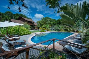 a pool with chairs and umbrellas next to a house at Pousada Mangabeiras in Ilha de Boipeba