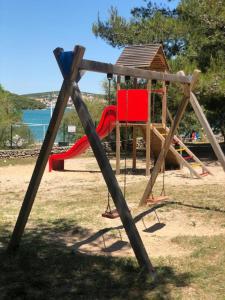 un parque infantil con 2 columpios y un tobogán en 2Pines House, en Jezera