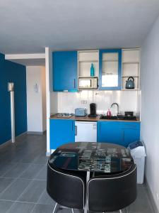 a kitchen with blue cabinets and a table in a room at Appartement naturiste PaulAna Port Ambonne 314 in Cap d'Agde