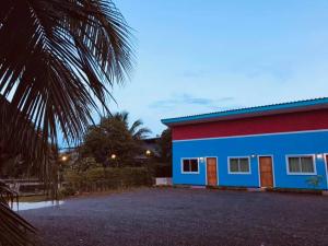 un edificio azul y rojo junto a una palmera en นิวเวฟภูเก็ต, en Ban Na Kok